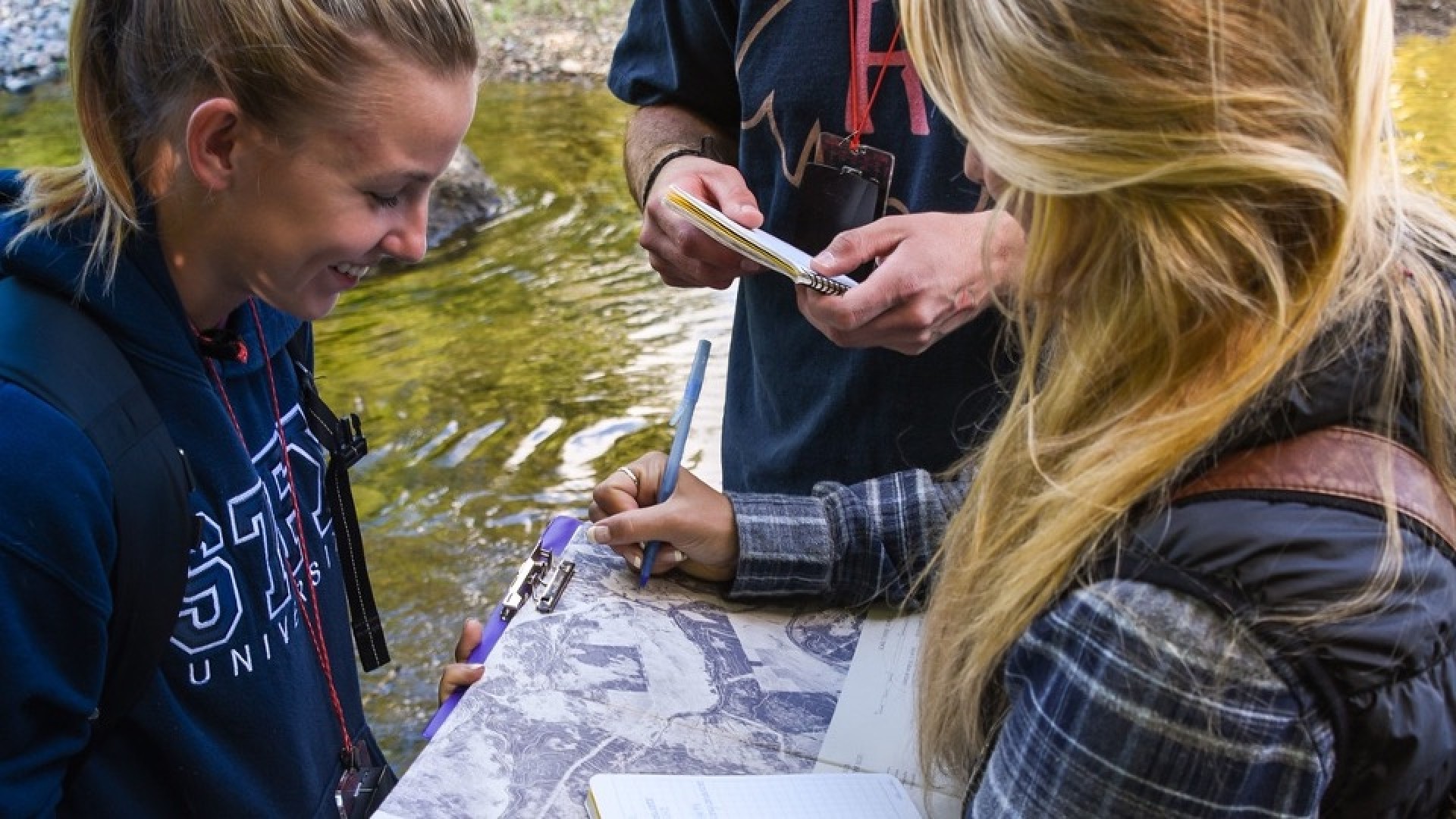Three students conducting research by the water. 
