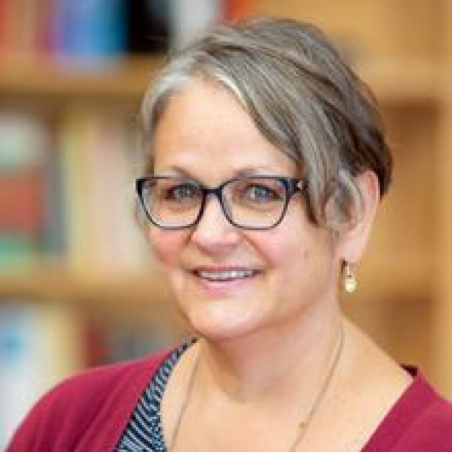 A woman with glasses is smiling for the camera