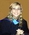 A young girl in a graduation gown smiles for the camera