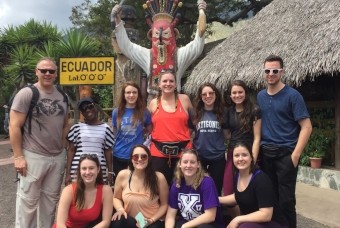 Group of people posing in front of "Ecuador" sign