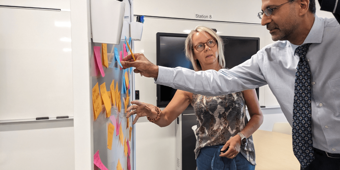 Two people at a white board talking.
