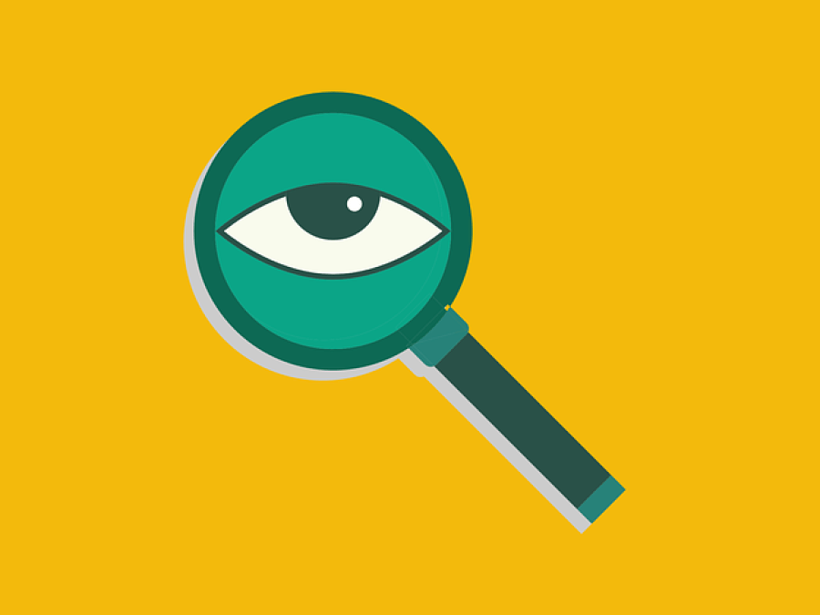 Magnifying glass with an eyeball in the centre, and a mustard yellow background