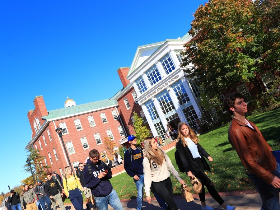 Students walking outside on a sunny day, leaving the Gerald Schwartz School of Business.