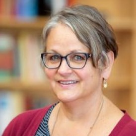 A woman with glasses is smiling for the camera